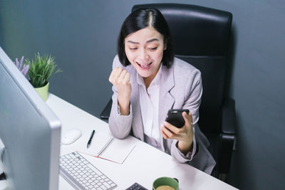 Young woman using phone while sitting on table