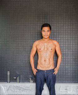 Portrait of shirtless man standing in bathroom