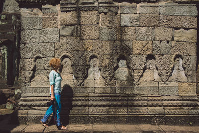 Side view of mid adult woman walking by old ruin temple