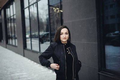 Portrait of young woman standing in city during winter