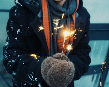 Midsection of woman holding lit sparkler