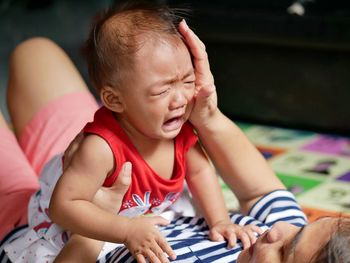 Mother carrying crying daughter at home