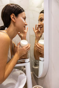 Side view of young woman washing hands in bathroom