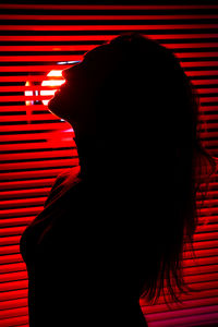 Close-up portrait of silhouette woman against illuminated wall