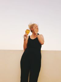 Midsection of woman holding ice cream against wall