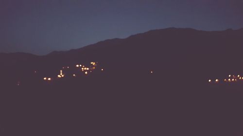 Silhouette of illuminated mountain against sky at night