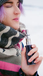 Woman smoking electronic cigarette during winter