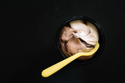 Close-up portrait of woman holding ice cream against black background
