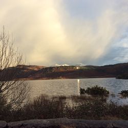 Scenic view of lake by mountains against sky