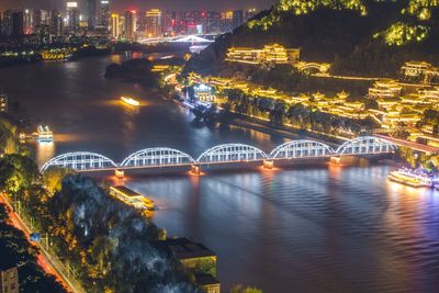 Illuminated bridge over river in city at night