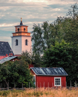 House amidst trees and building against sky