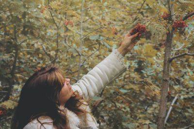 Young woman holding fruits growing on tree in forest