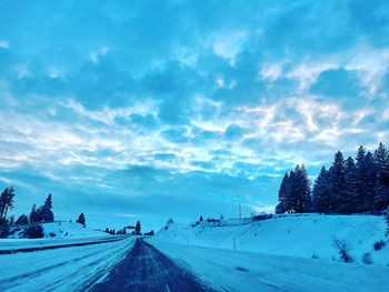 Road amidst snowcapped landscape against sky during winter