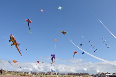 Low angle view of kites flying against blue sky