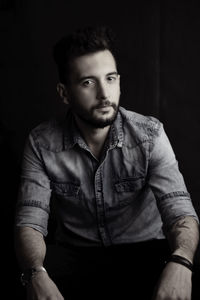 Portrait of young man against black background