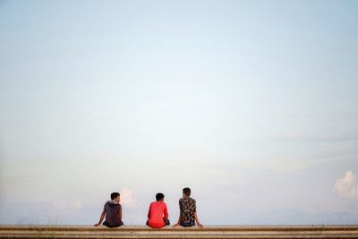 Rear view of people sitting on the beach