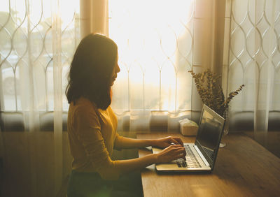 Side view of woman using mobile phone at home