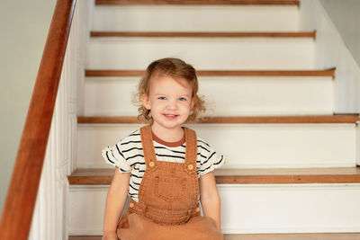 Portrait of cute girl sitting on staircase at home