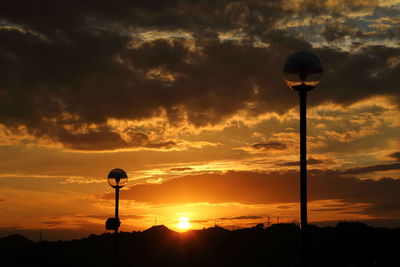 Low angle view of street light against orange sky