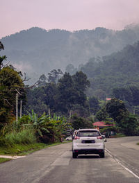 Car on road by mountains against sky