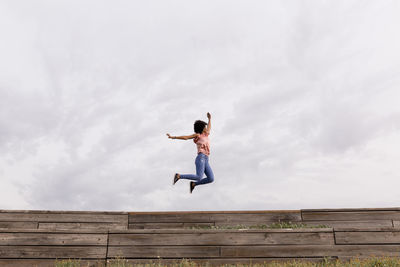 Woman jumping outdoors against sky