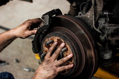 Cropped hands of mechanic repairing wheel at workshop