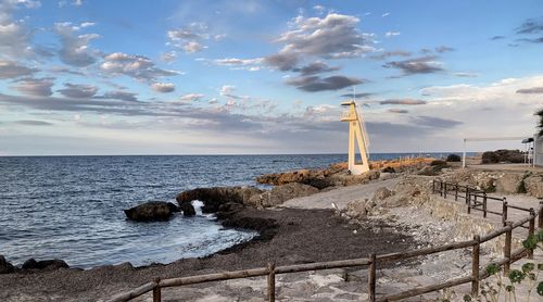 Lighthouse by sea against sky