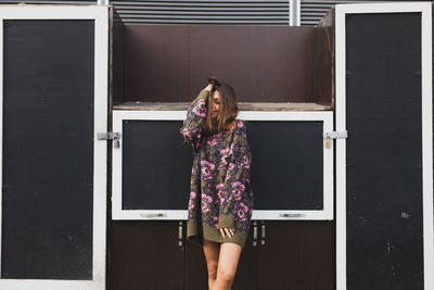 Young woman smiling while standing against doors