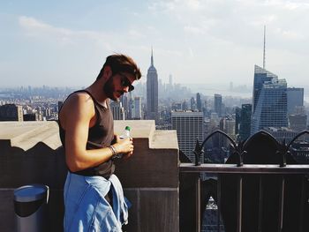 Young woman using mobile phone while standing on retaining wall