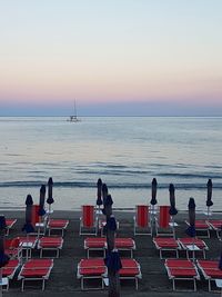 People on beach by sea against sky during sunset