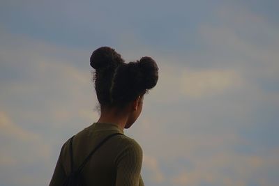 Rear view of woman with hair buns standing against sky