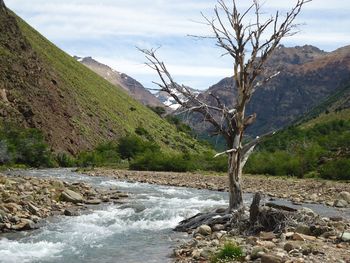 Scenic view of river by mountains against sky