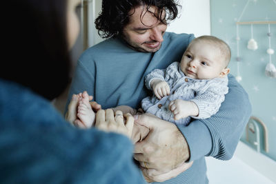 Smiling father and mother playing with baby boy at home