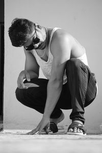Rear view of young man sitting against wall