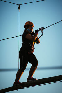 Low angle view of man holding rope against sky