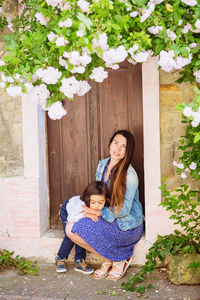 Woman and handsome baby boy sitting near the ancient door