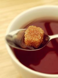 Close-up of brown sugar in spoon over coffee