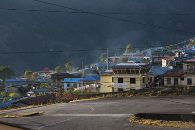 Road by buildings against sky in city