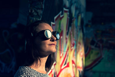 Close-up of woman wearing sunglasses by wall
