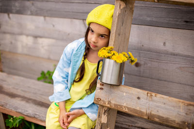 Portrait of girl standing by wooden wall