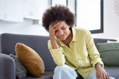 Young woman sitting on sofa at home