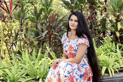 Young woman standing against plants