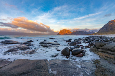 Rocks on beach against sky during sunset