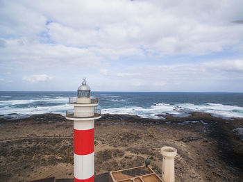 Lighthouse by sea against sky