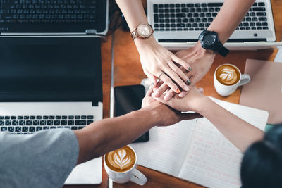 High angle view of business people stacking hands over table in office