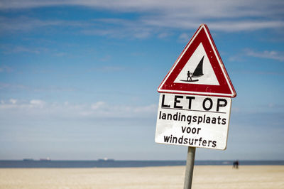 Information sign on a beach against sky
