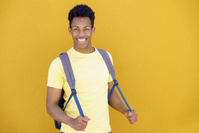 Portrait of a smiling young man against yellow background