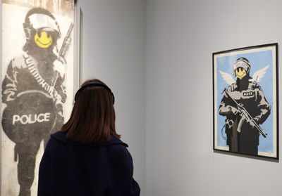 Rear view of woman standing against wall in museum