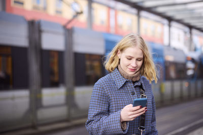 Woman using cell phone at tram stop