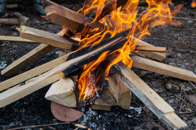 A fire burns in a campfire with a red fire in the background.